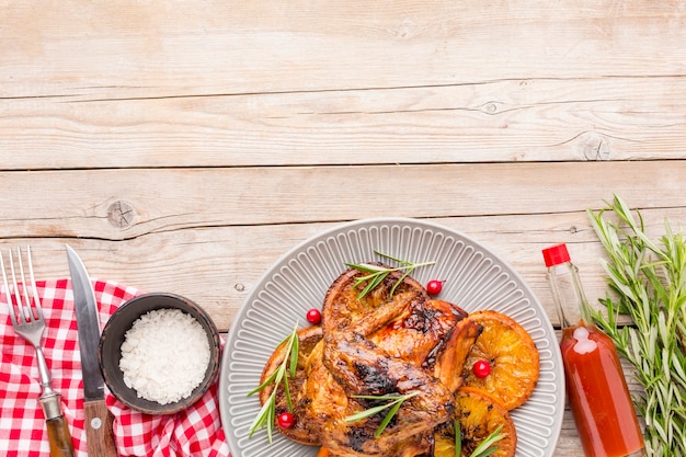 Top view baked chicken and orange slices on plate with sea salt and sauce