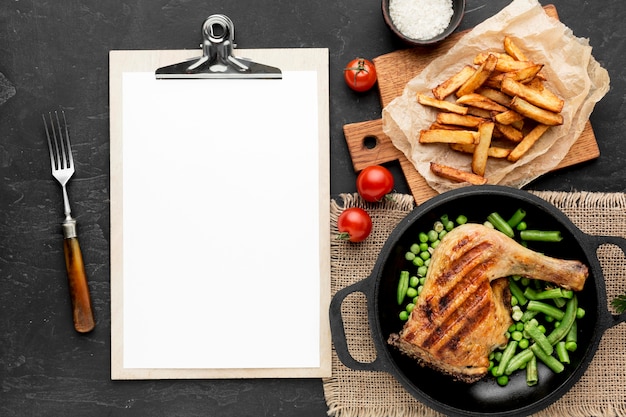 Free photo top view baked chicken and pea pods in pan with potatoes and blank clipboard