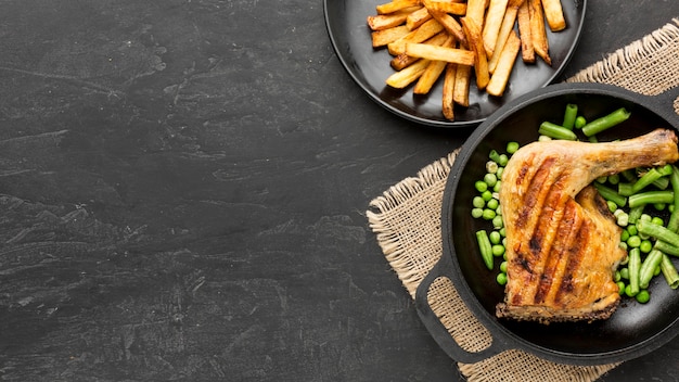 Top view baked chicken and pea pods in pan with potatoes and copy-space