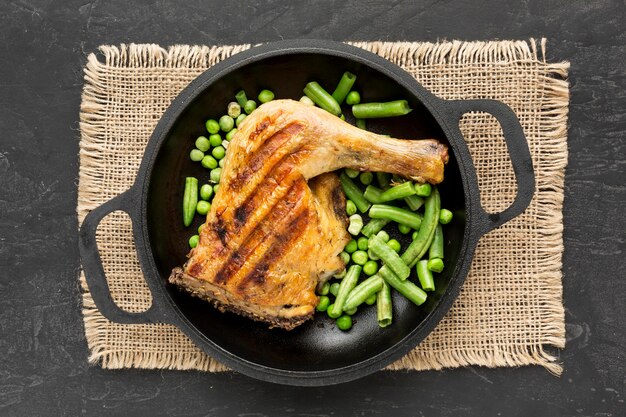 Top view baked chicken and pea pods in pan