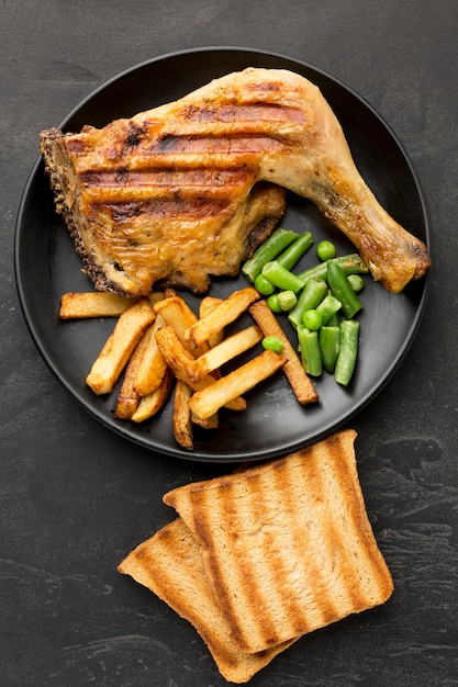 Foto gratuita vista dall'alto di pollo al forno e patate sulla piastra con pane tostato