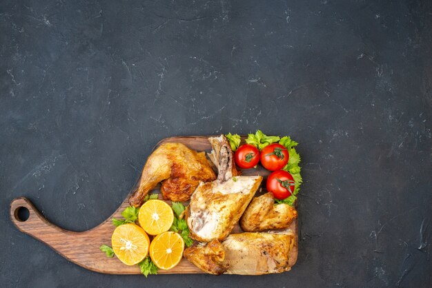 Top view baked chicken tomatoes lemon slices on wooden board