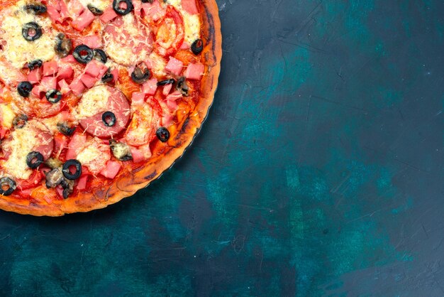 Top view baked delicious pizza with olives sausages and cheese on the blue background.