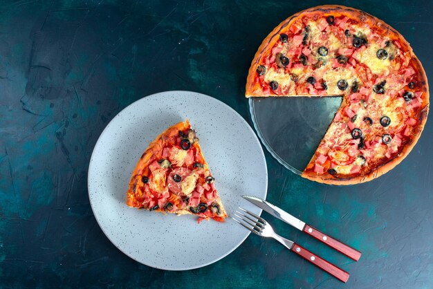 Вид сверху испеченная вкусная пицца с оливками, сосисками и сыром на синем столе.