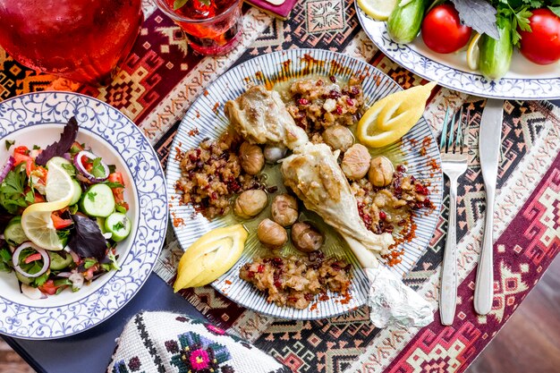 Top view baked lamb leg with chestnuts minced meat lemon and vegetable salad