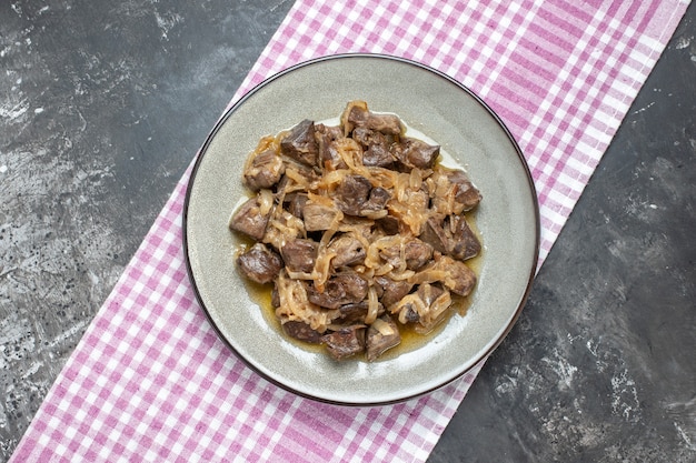 Top view baked liver and onion on oval plate on tablecloth