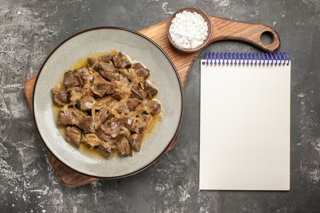 Top view baked liver and onion on plate sea salt on chopping board