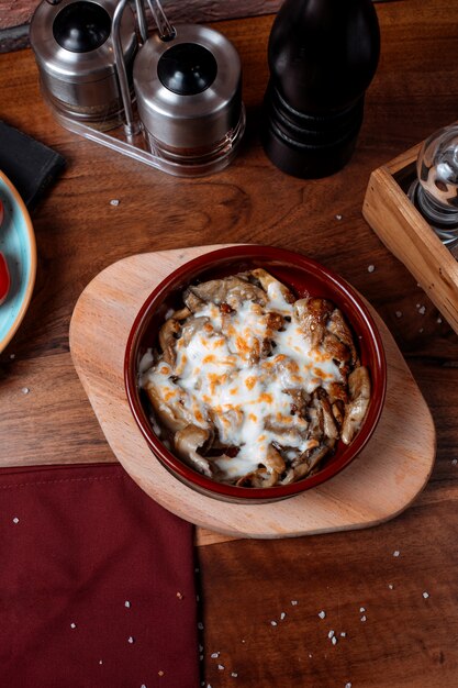 Top view of baked mushroom with cheese in a clay bowl