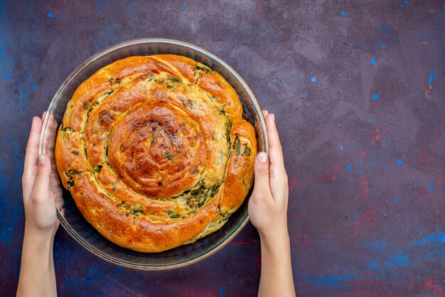 Top view baked pastry with greens inside on the dark background.