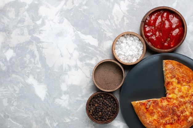 Top view baked pizza with different seasonings on a white desk