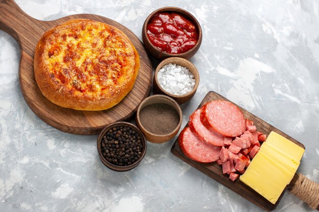 Top view baked pizza with different seasonings on white desk