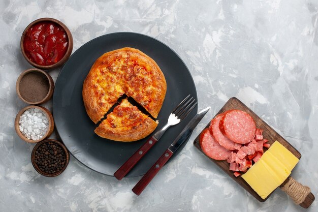 Top view baked pizza with seasonings on light