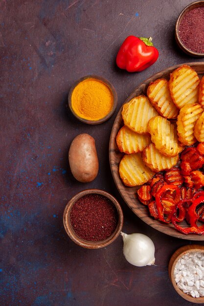 Vista dall'alto di patate al forno con verdure cotte su uno spazio buio