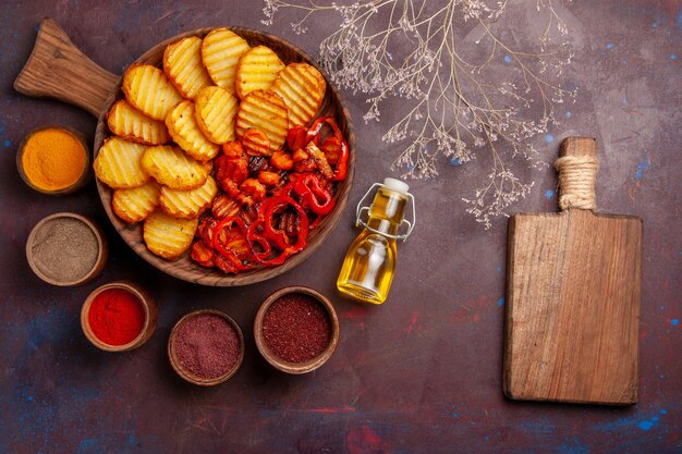 Top view baked potatoes with different seasonings on a dark space