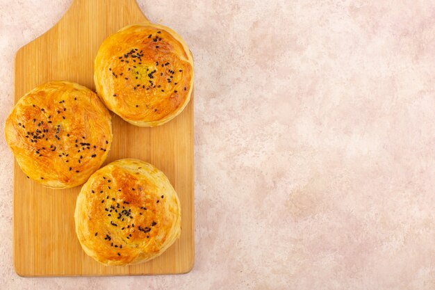 Вид сверху запеченных квогалов круглой формы, вкусных горячих свежих из духовки на коричневом столе