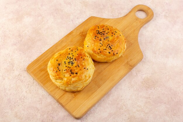 Вид сверху запеченных квогалов круглой формы, вкусных горячих свежих из духовки на коричневом деревянном столе