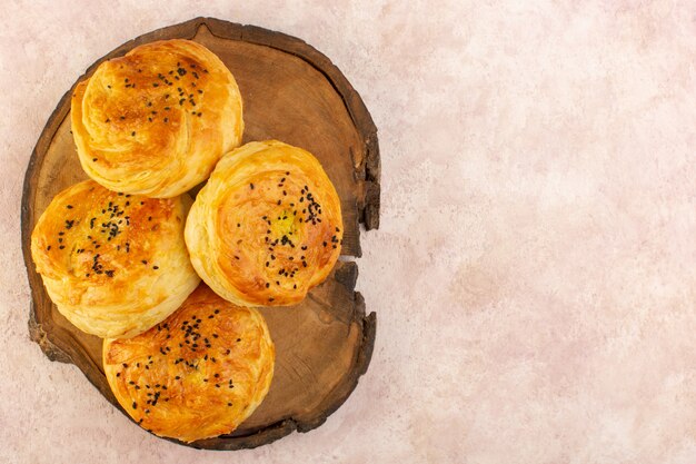 Вид сверху запеченных квогалов круглой формы, вкусных горячих свежих из духовки на коричневом деревянном столе