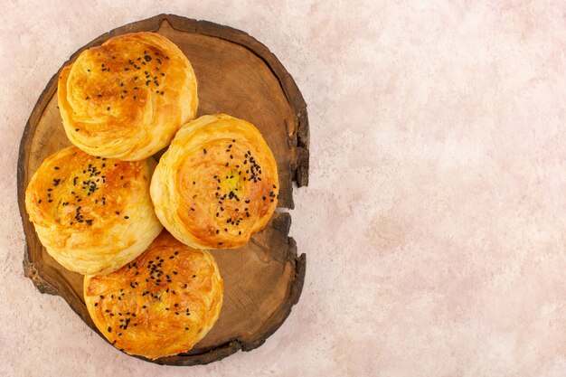 Free photo a top view baked qogals round shaped tasty hot fresh off the oven on the brown wooden desk