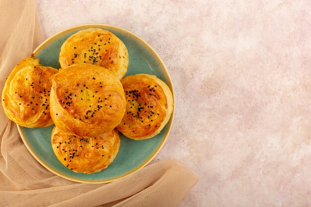 Вид сверху запеченные квогалы круглой формы вкусные горячие свежие из духовки внутри зеленой тарелки