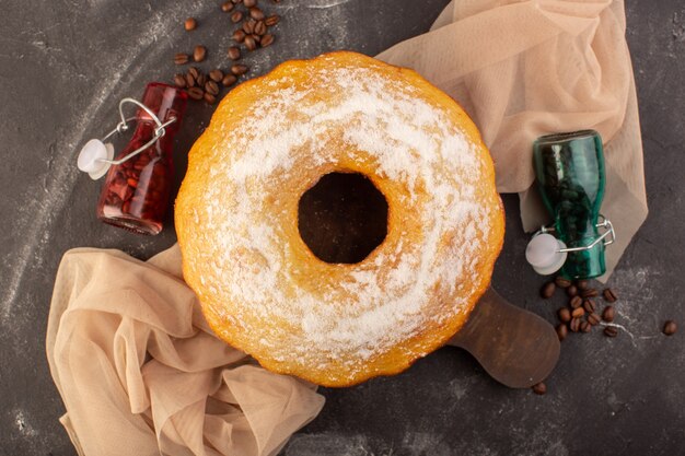 A top view baked round cake with sugar powder and coffee seeds on the wooden desk 