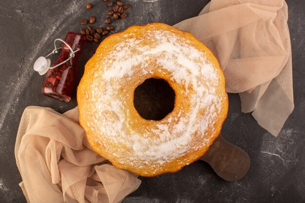 A top view baked round cake with sugar powder and coffee seeds on the wooden desk 