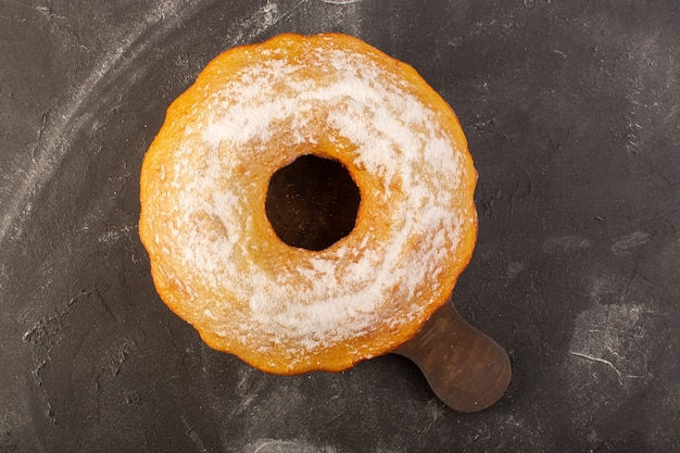 A top view baked round cake with sugar powder on the wooden desk 