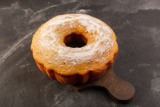 A top view baked round cake with sugar powder on the wooden desk 