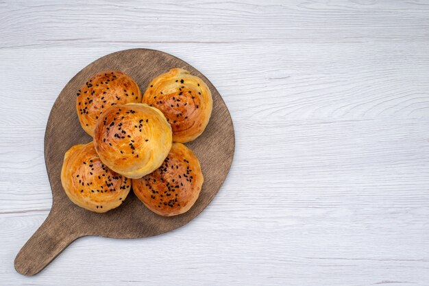 Top view baked tasty buns on the wooden desk and light background bun bread food meal