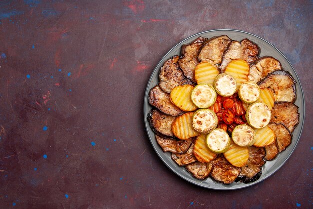 Top view baked vegetables potatoes and eggplants fresh off the oven on dark space