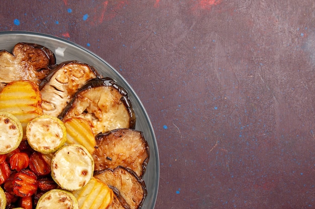 Top view baked vegetables potatoes and eggplants fresh off the oven on dark space