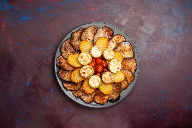Top view baked vegetables potatoes and eggplants inside plate on a dark space