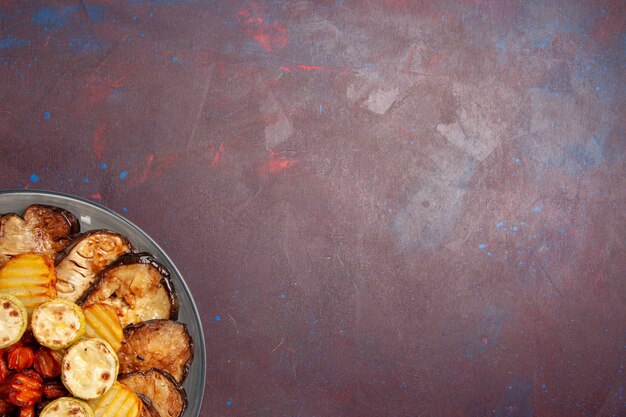 Top view baked vegetables potatoes and eggplants inside plate on dark space