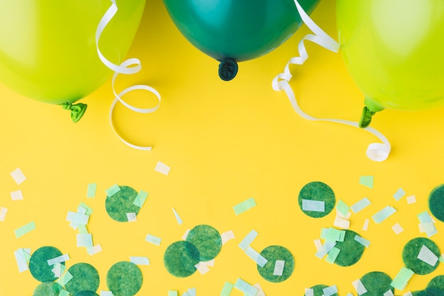 Top view of balloons and confetti frame on yellow background