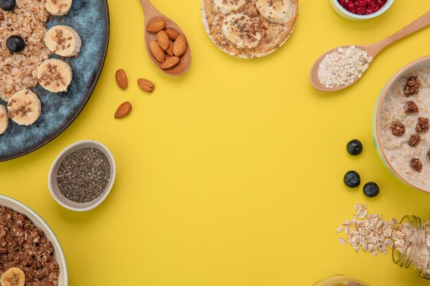 Top view of banana blackthorn oatmeal banana crispbread snack banana walnut and walnut milk oatmeals with chia seeds spoons full of almond and oat on yellow background