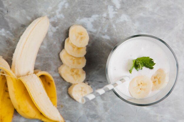 Top view of banana and glass on marble background