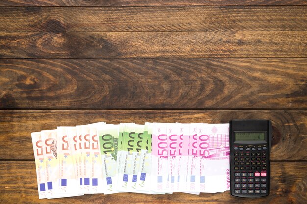 Top view banknotes and calculator on wooden background