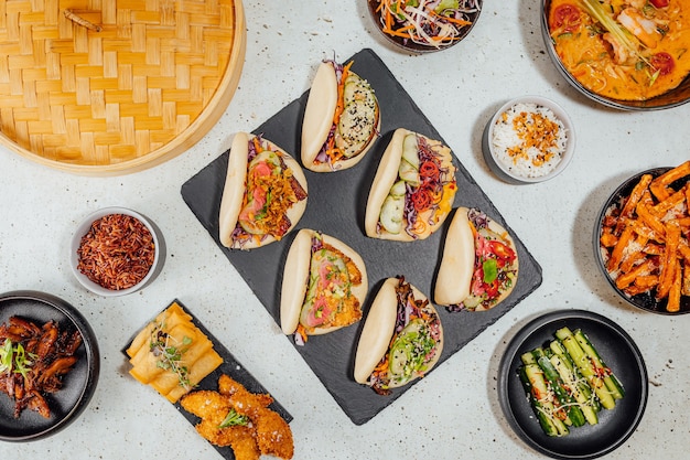 Top view of bao buns surrounded by different dishes on a white table