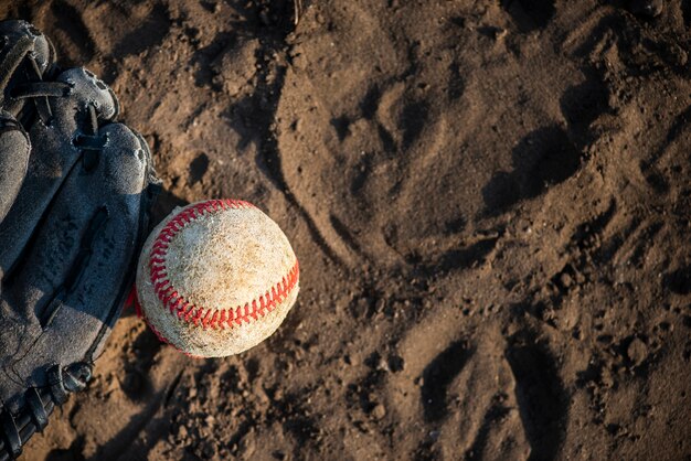 Top view of baseball and glove on dirt