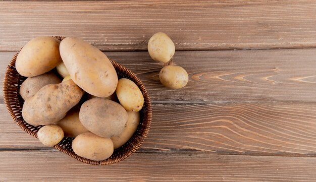 Top view of basket full of potatoes on wooden background with copy space 2