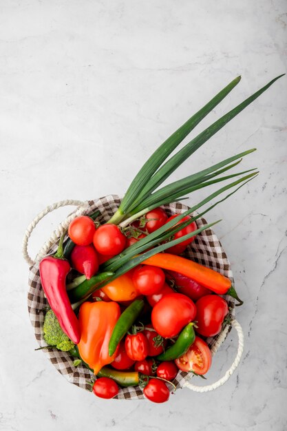 Top view of basket full of vegetables on white surface