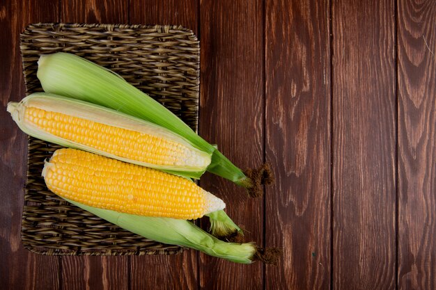 Top view of basket plate with corns on left side and wooden surface with copy space