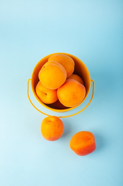 A top view basket with apricots sweet fresh mellow fruits inside yellow basket isolated