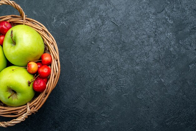 Top view basket with fruits apples and sweet cherries on dark background fruit berry composition freshness