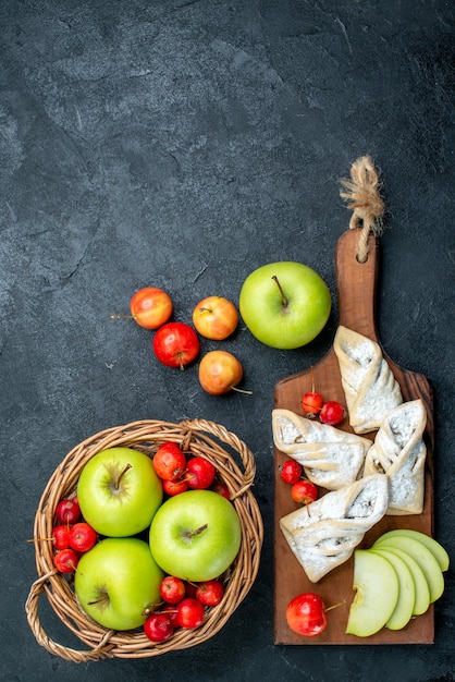 Foto gratuita il canestro di vista superiore con le mele verdi della frutta e le ciliege dolci sullo scrittorio grigio scuro fruttifica l'albero dolce di freschezza della composizione