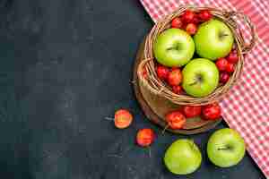 Free photo top view basket with fruits green apples and sweet cherries on dark grey surface fruits berry composition freshness tree