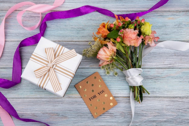 Top view of beautiful and colorful bouquet of flowers tied with white ribbon on grey wood