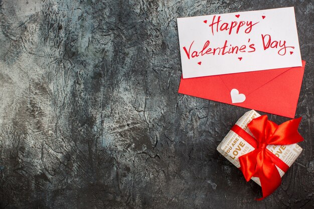 氷のような暗い背景の左側にバレンタインデーの赤いリボンで結ばれた美しいギフトボックスの上面図