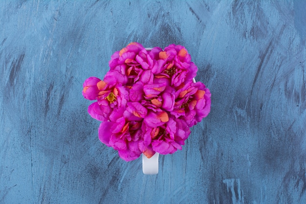 Free photo top view of beautiful purple flowers in a cup on blue.