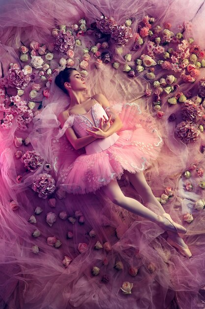花に囲まれたピンクのバレエチュチュの美しい若い女性の上面図