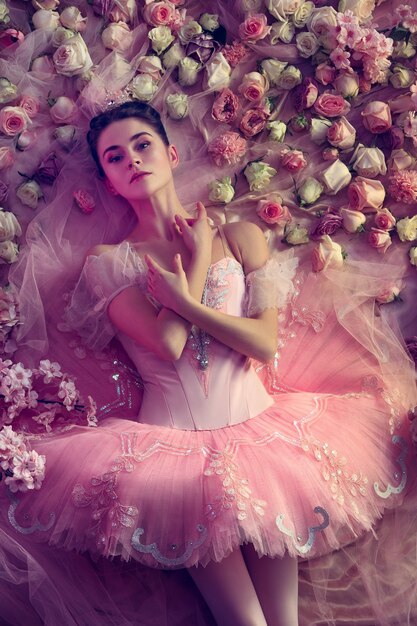 Вид сверху красивой молодой женщины в розовой балетной пачке в окружении цветов